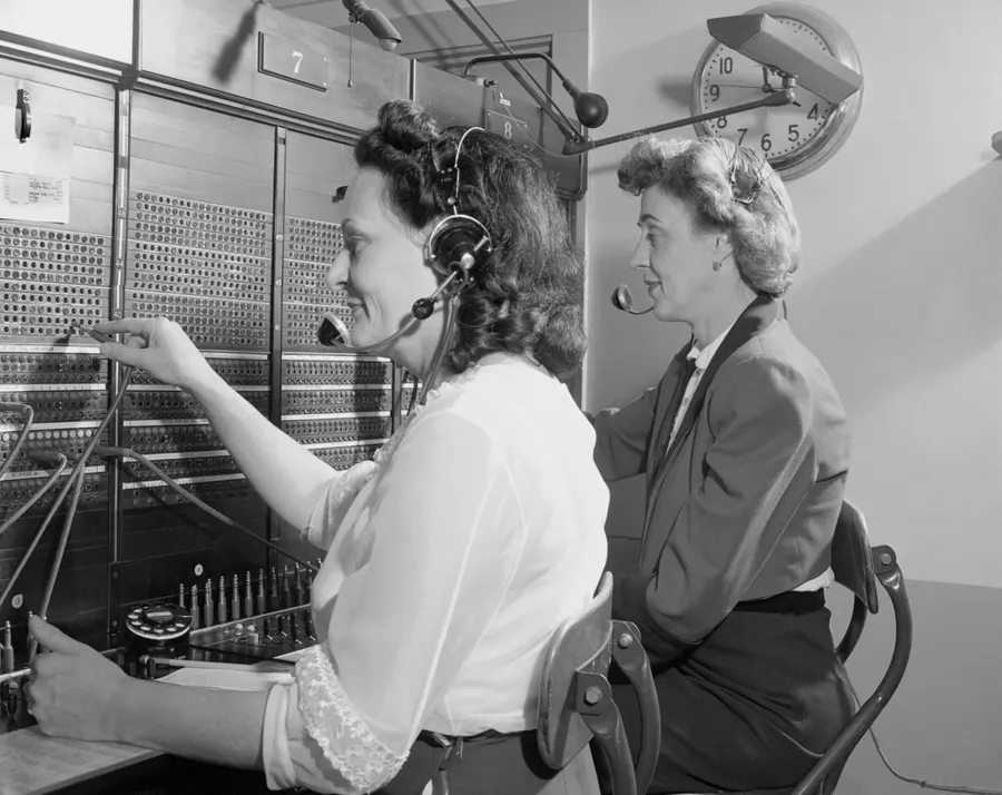 Two telephone operators at an old switchboard.